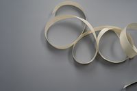 Two loops of pale satin ribbon on a grey studio background